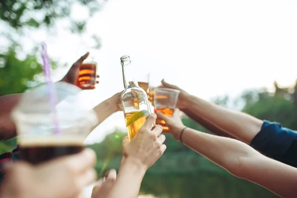 Bottiglie di birra nelle mani dei popoli su sfondo cielo blu — Foto Stock