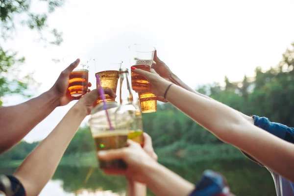 Botellas de cerveza en las manos de la gente en el fondo del cielo azul — Foto de Stock