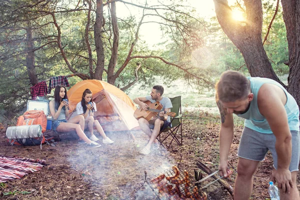 Party, camping of men and women group at forest. They relaxing, singing a song and cooking barbecue — Stock Photo, Image