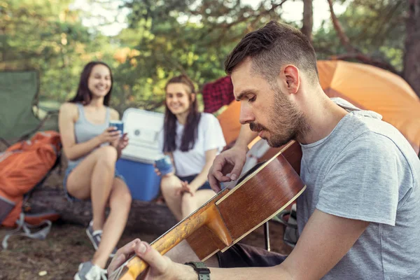 Fiesta, camping de hombres y mujeres grupo en el bosque. Se relajan, cantan una canción — Foto de Stock