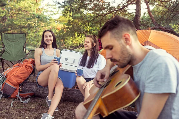 Impreza, camping grupy mężczyzn i kobiet, w lesie. One relaksujący, śpiewając piosenkę — Zdjęcie stockowe