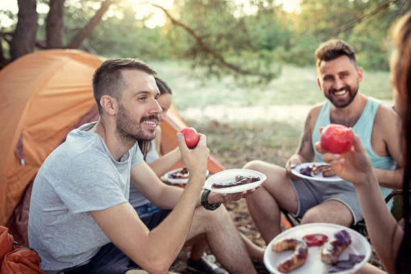 Fiesta, camping de hombres y mujeres grupo en el bosque. Ellos relajante y comer barbacoa —  Fotos de Stock