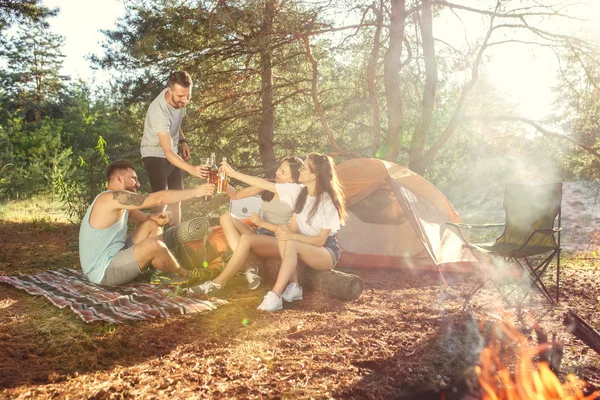 Fiesta, camping de hombres y mujeres grupo en el bosque. Se relajan — Foto de Stock