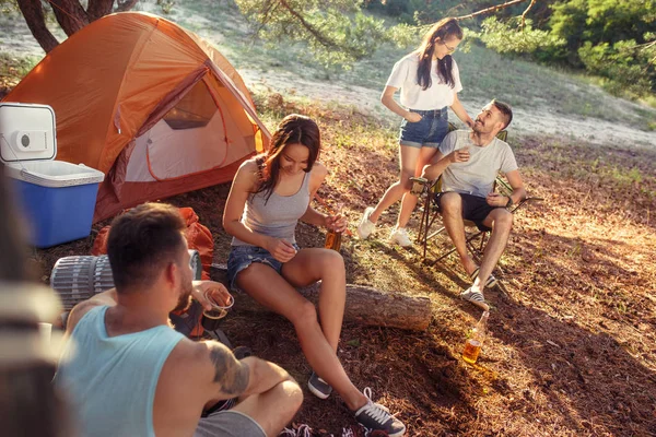 Fiesta, camping de hombres y mujeres grupo en el bosque. Se relajan —  Fotos de Stock