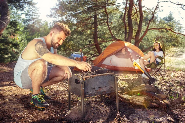 Fiesta, camping de hombres y mujeres grupo en el bosque. Se relajan —  Fotos de Stock