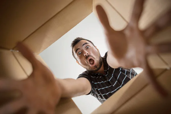 Homem desembalagem e caixa de papelão de abertura e olhando para dentro — Fotografia de Stock
