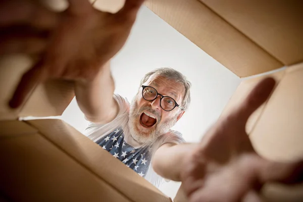 Omul despachetează și deschide cutie de carton și se uită în interior — Fotografie, imagine de stoc