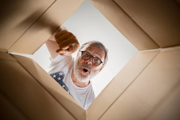 Man unpacking and opening carton box and looking inside — Stock Photo, Image