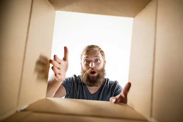 Man unpacking and opening carton box and looking inside — Stock Photo, Image