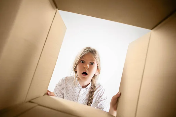 La chica desempacando y abriendo la caja de cartón y mirando dentro —  Fotos de Stock