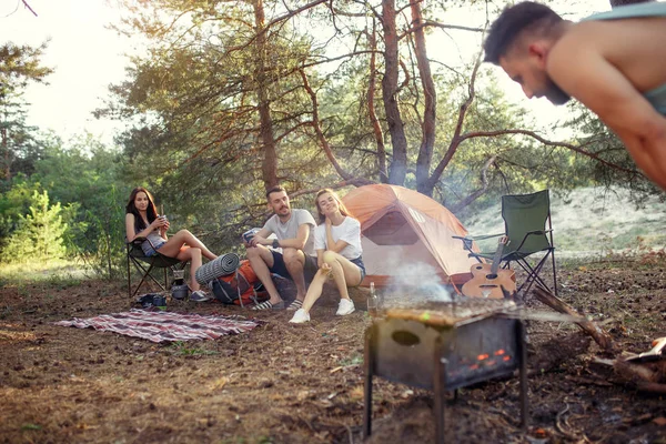 Party, camping of men and women group at forest. They relaxing, singing a song and cooking barbecue