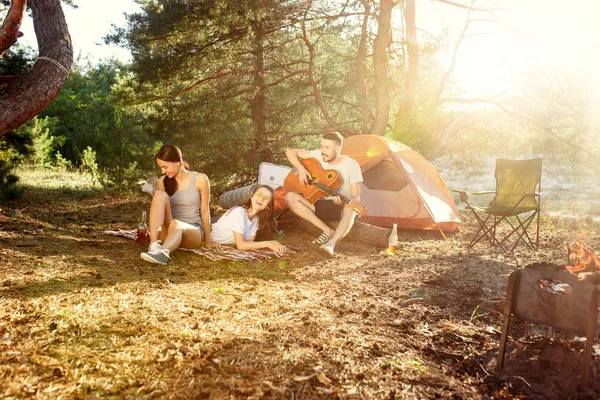 Party, camping of men and women group at forest. They relaxing, singing a song