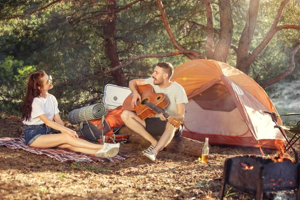 Fiesta, camping de hombres y mujeres grupo en el bosque. Se relajan, cantan una canción — Foto de Stock