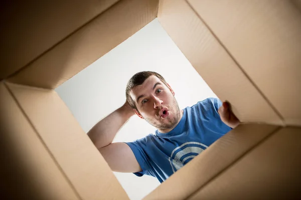 Hombre desembalaje y apertura caja de cartón y mirando dentro — Foto de Stock