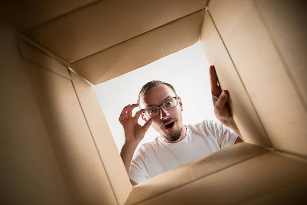 Homem desembalagem e caixa de papelão de abertura e olhando para dentro — Fotografia de Stock