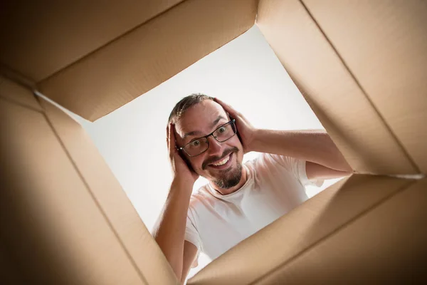 Homem desembalagem e caixa de papelão de abertura e olhando para dentro — Fotografia de Stock