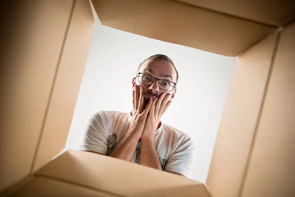 Homem desembalagem e caixa de papelão de abertura e olhando para dentro — Fotografia de Stock