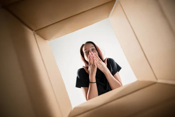 Жінка розпаковує і відкриває картонну коробку і дивиться всередину — стокове фото
