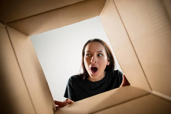 Vrouw uitpakken en openen van kartonnen doos en op zoek binnen — Stockfoto