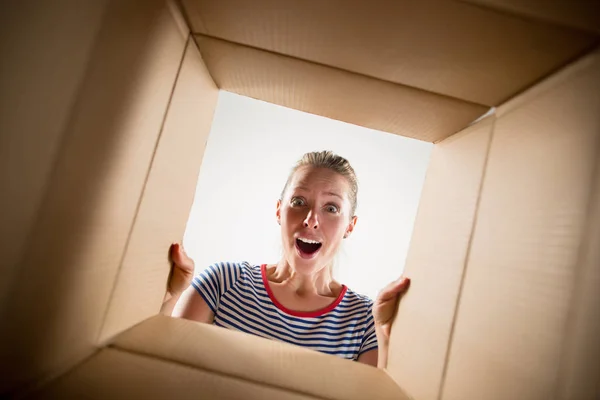 Vrouw uitpakken en openen van kartonnen doos en op zoek binnen — Stockfoto