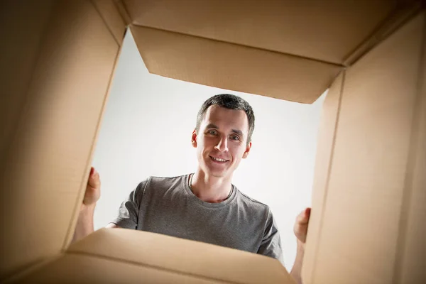 Hombre desembalaje y apertura caja de cartón y mirando dentro — Foto de Stock