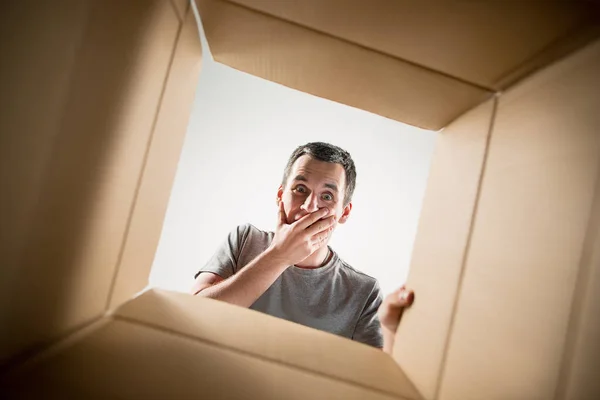 Hombre desembalaje y apertura caja de cartón y mirando dentro —  Fotos de Stock