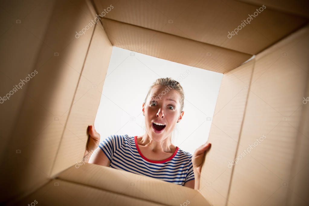 Woman unpacking and opening carton box and looking inside