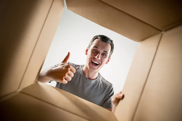 Hombre desembalaje y apertura caja de cartón y mirando dentro —  Fotos de Stock