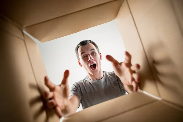 Man unpacking and opening carton box and looking inside — Stock Photo, Image
