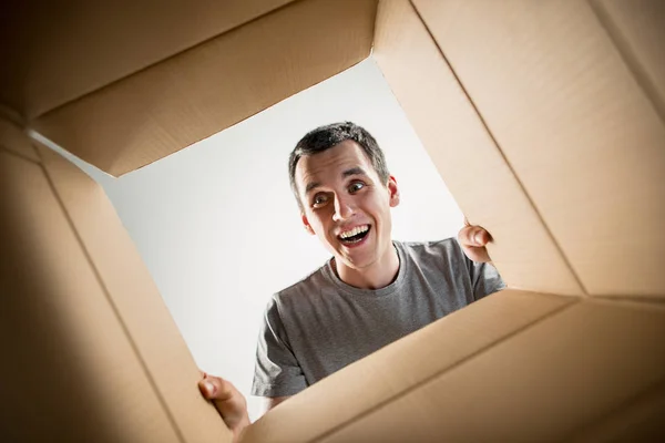 Hombre desembalaje y apertura caja de cartón y mirando dentro —  Fotos de Stock