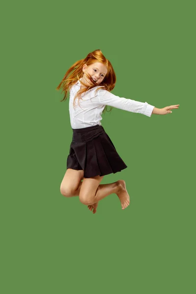 Молода щаслива біла дівчина-підліток стрибає в повітрі, ізольована на зеленому фоні — стокове фото