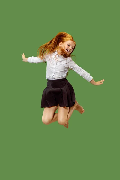 Молода щаслива біла дівчина-підліток стрибає в повітрі, ізольована на зеленому фоні — стокове фото