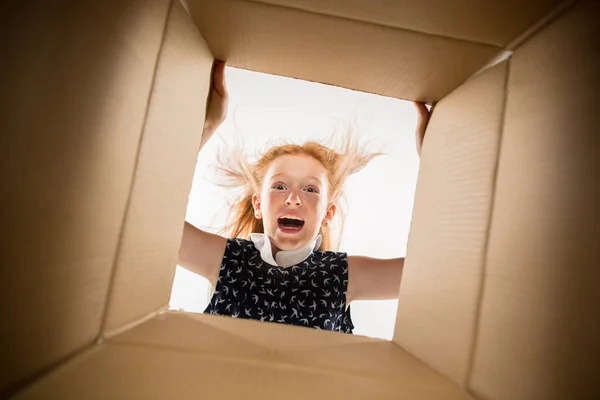 Het meisje uitpakken en openen van kartonnen doos en op zoek binnen — Stockfoto