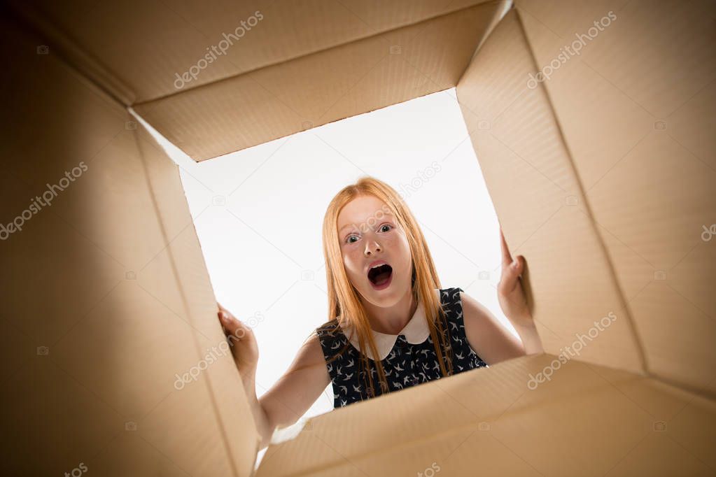 The girl unpacking and opening carton box and looking inside