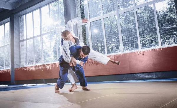 Два борца дзюдо демонстрируют техническое мастерство, практикуя боевые искусства в бойцовском клубе — стоковое фото