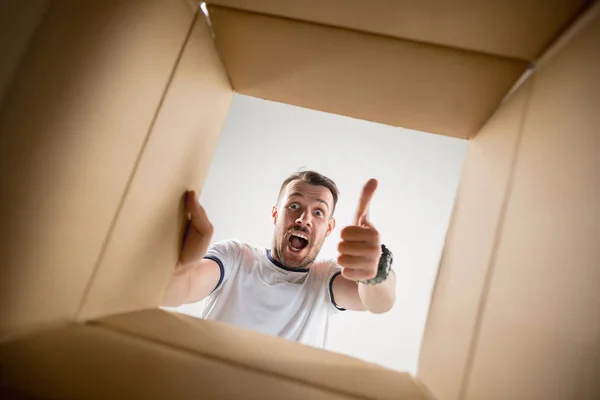 Mann packt Karton aus und schaut hinein — Stockfoto