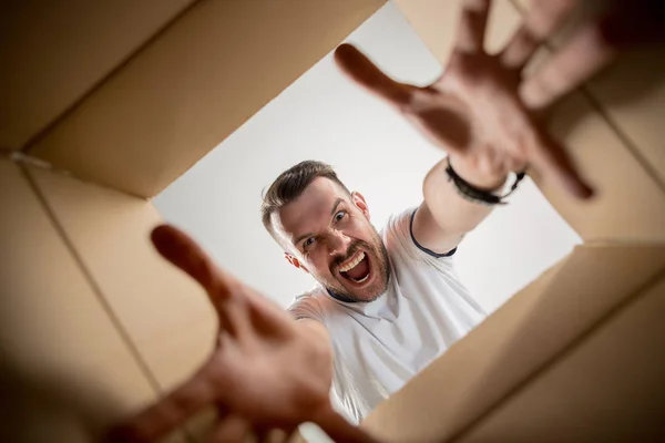 Homem desembalagem e caixa de papelão de abertura e olhando para dentro — Fotografia de Stock