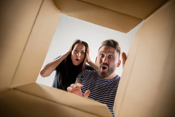 The couple unpacking and opening carton box and looking inside — Stock Photo, Image