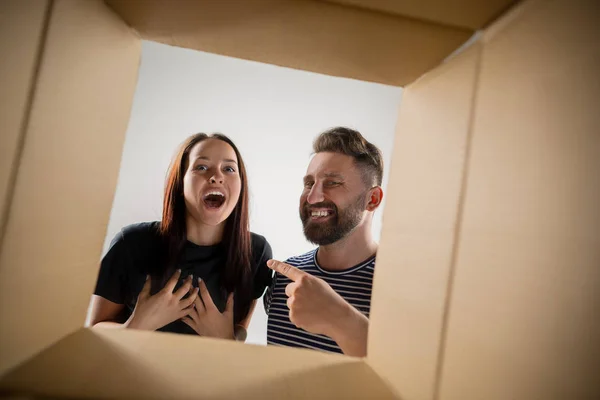 La pareja desempacando y abriendo la caja de cartón y mirando dentro —  Fotos de Stock