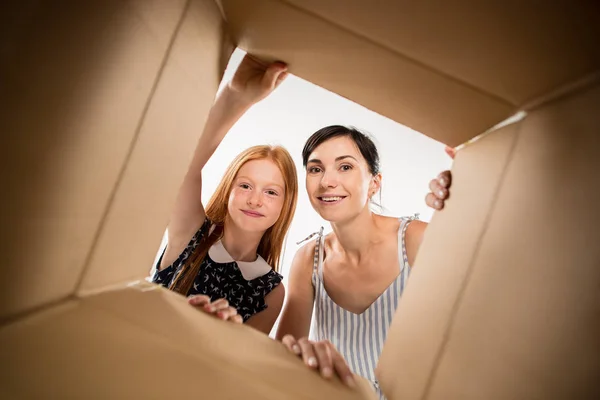 Mãe e filha desembalagem e abertura caixa de papelão e olhando para dentro — Fotografia de Stock