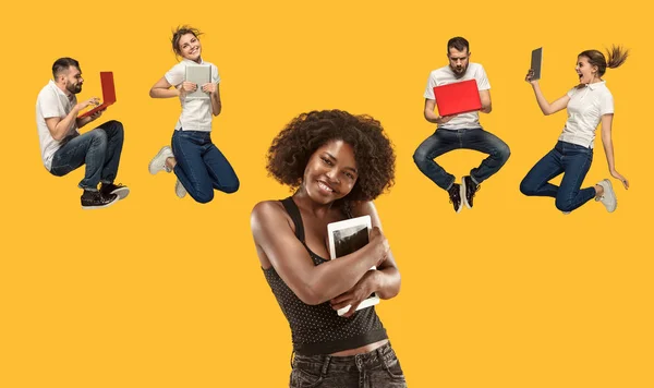Los jóvenes y felices saltando mujeres y hombres con computadoras portátiles —  Fotos de Stock