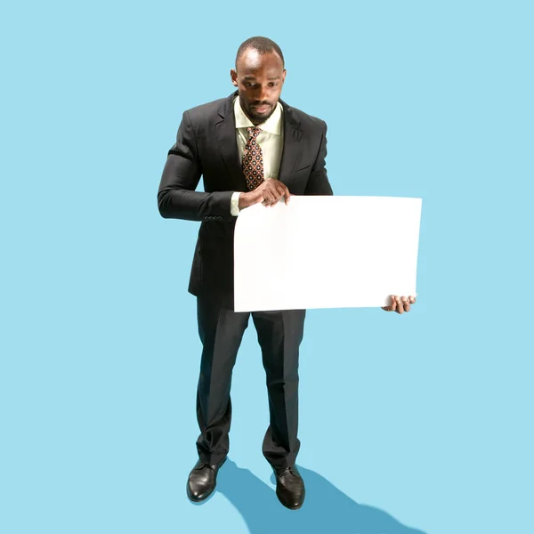 Business man holding a blank banner isolated on blue background — Stock Photo, Image