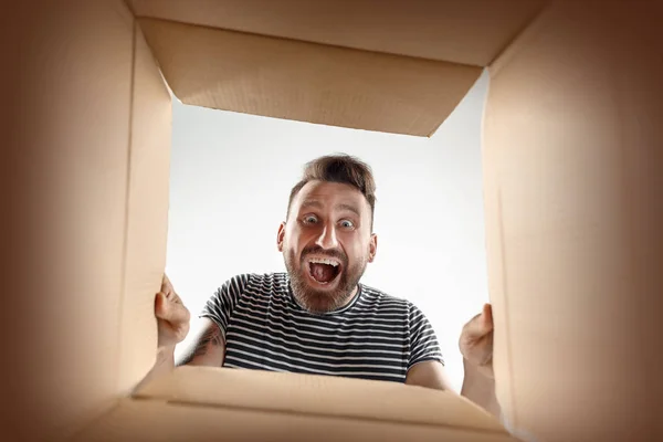 Чоловік розпаковує і відкриває картонну коробку і дивиться всередину — стокове фото