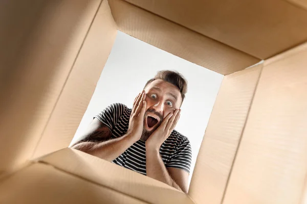 Mann packt Karton aus und schaut hinein — Stockfoto