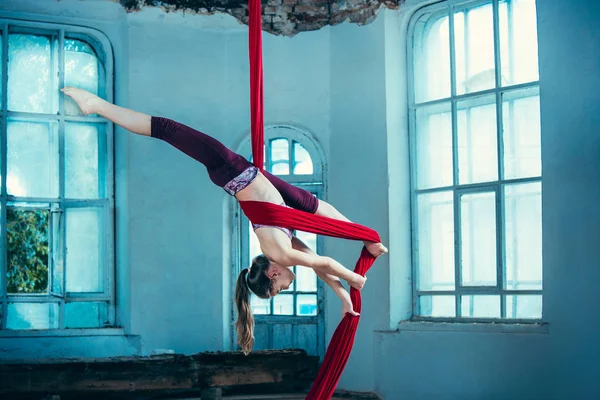 Graceful gymnast performing aerial exercise at loft