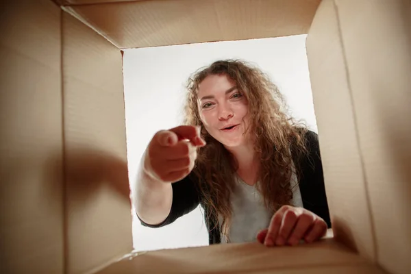 Woman unpacking and opening carton box and looking inside
