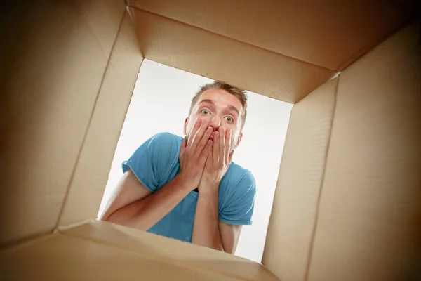 Homem sorrindo, desembalando e abrindo caixa de papelão e olhando para dentro — Fotografia de Stock
