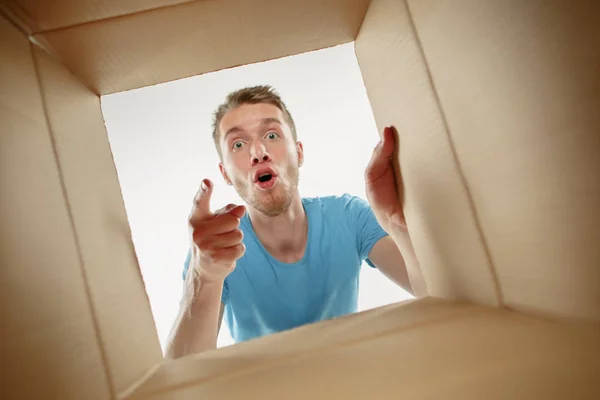 Hombre sonriendo, desempacando y abriendo la caja de cartón y mirando dentro —  Fotos de Stock