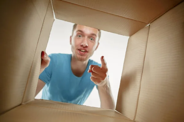 Чоловік посміхається, розпаковує і відкриває картонну коробку і дивиться всередину — стокове фото