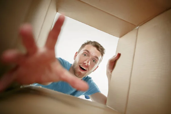 Homem sorrindo, desembalando e abrindo caixa de papelão e olhando para dentro — Fotografia de Stock